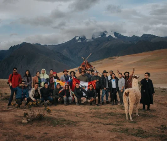 A diverse group poses with alpacas against the majestic Andes Mountains, Peru.