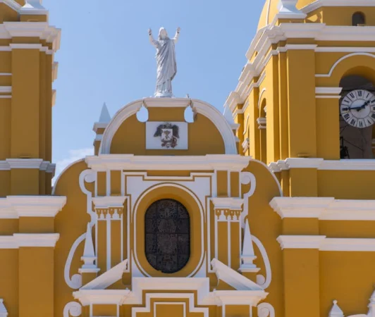 Close-up of a vibrant yellow colonial church facade in Trujillo, Peru, under a clear sky.